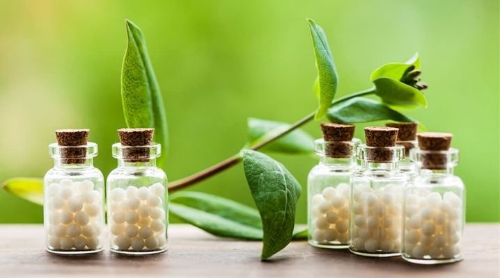 Homeopati için gerekli olan şişe içinde beyaz bitkisel malzeme ve çiçekler